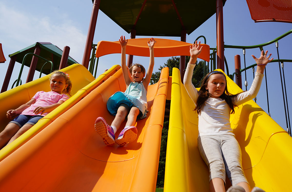 Children Sliding Down Playground Slide